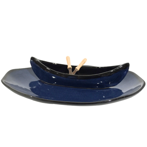 Blue and black canoe on a plate with two spatulas as paddles.