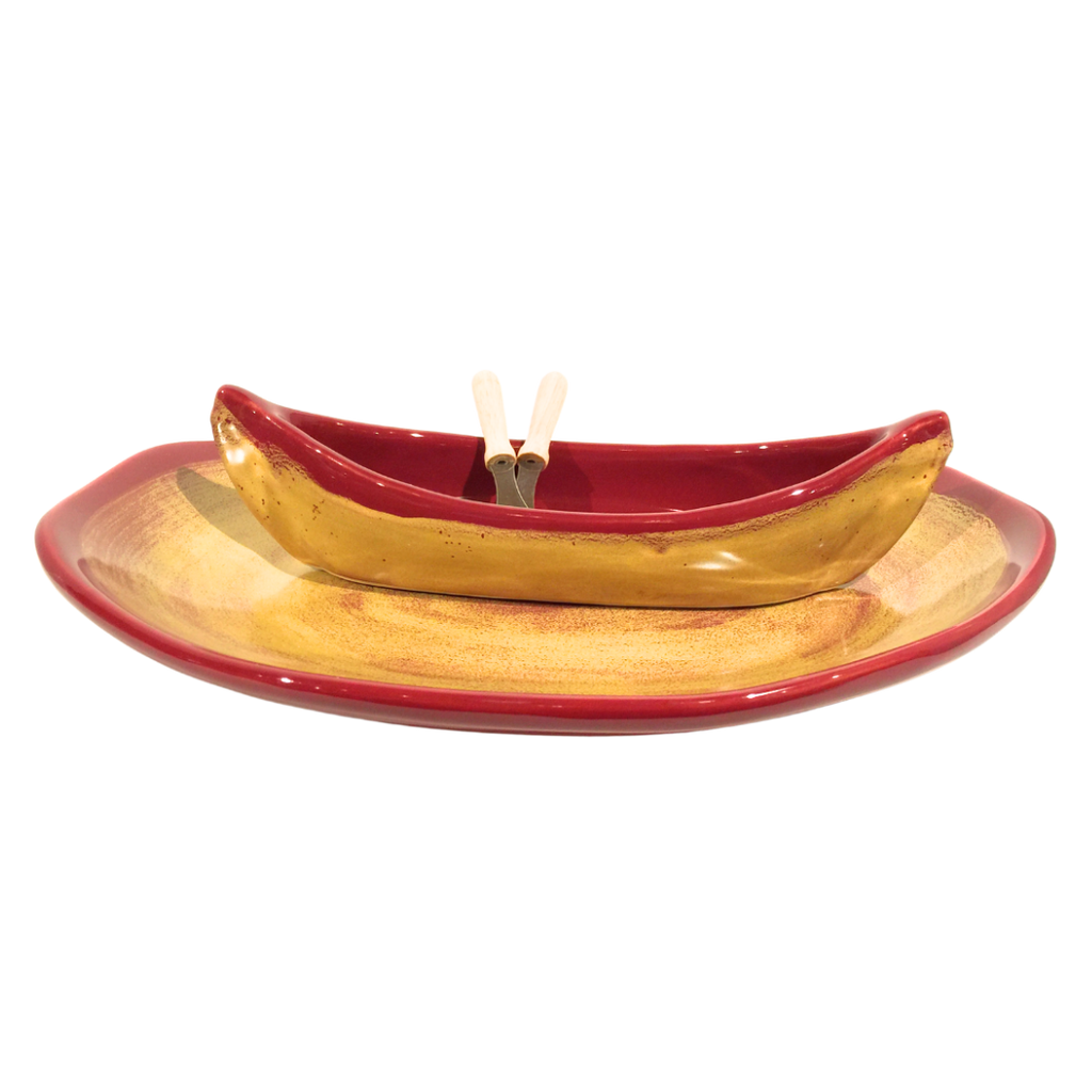 Red and gold canoe on a plate with two spatulas as paddles.